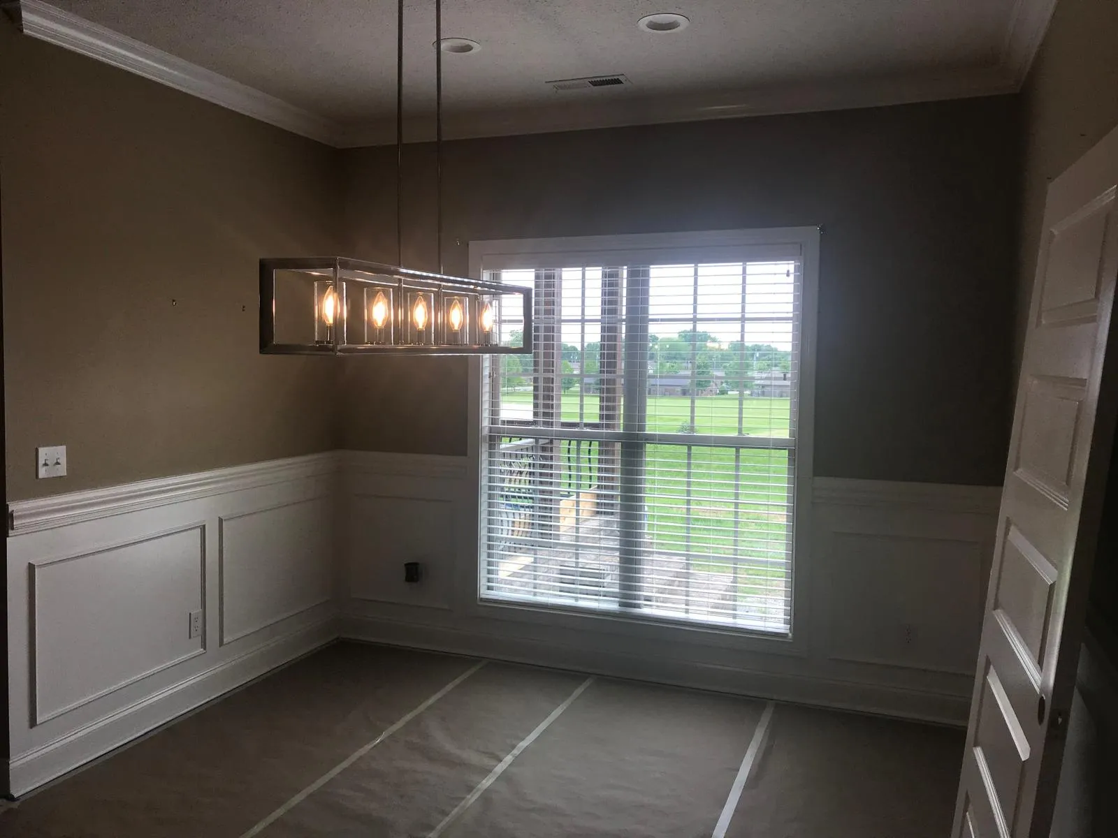 Finished dining room with taupe walls and white wainscoting